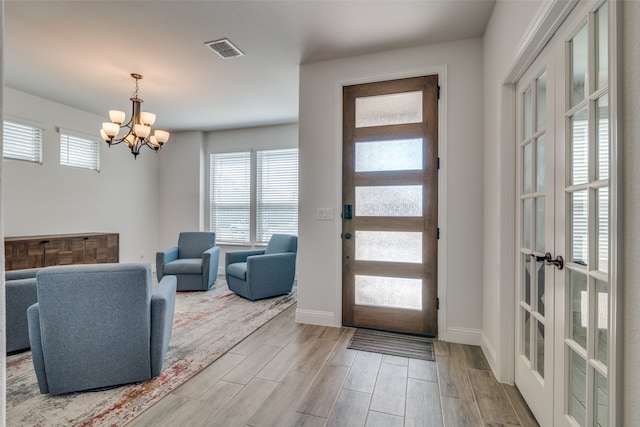 foyer with light hardwood / wood-style flooring and an inviting chandelier