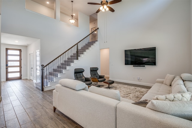 living room with a towering ceiling, wood-type flooring, and ceiling fan