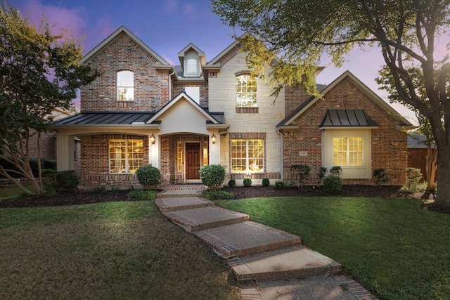 view of front of property with covered porch and a lawn