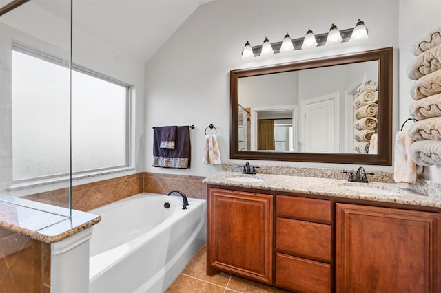 bathroom featuring lofted ceiling, a tub to relax in, tile patterned floors, and vanity