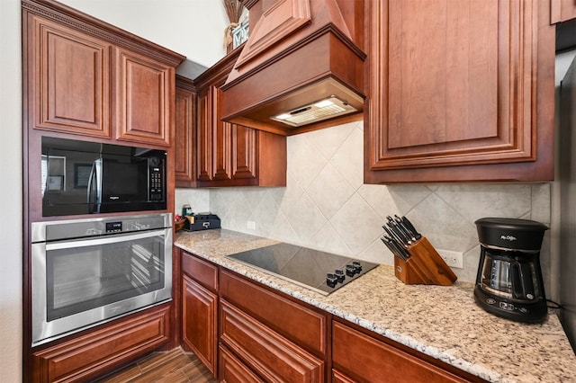 kitchen featuring black appliances, hardwood / wood-style flooring, backsplash, and light stone countertops