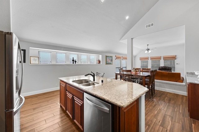 kitchen featuring an island with sink, vaulted ceiling, sink, and appliances with stainless steel finishes