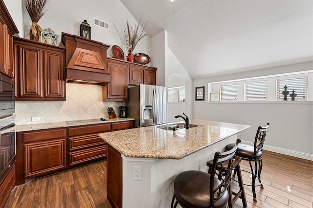 kitchen featuring appliances with stainless steel finishes, sink, an island with sink, and dark hardwood / wood-style flooring