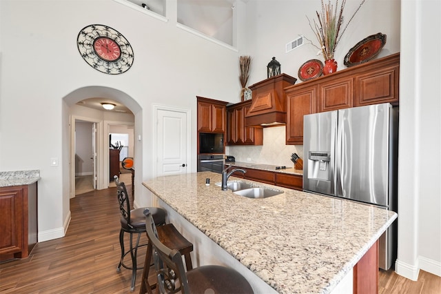 kitchen featuring dark wood-type flooring, a kitchen island with sink, sink, and black appliances