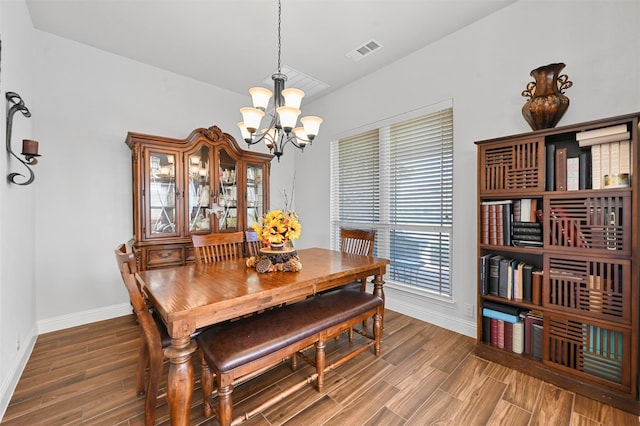 dining space featuring dark wood-type flooring and a notable chandelier