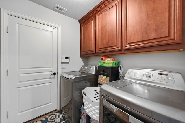 laundry area featuring a textured ceiling, cabinets, and independent washer and dryer