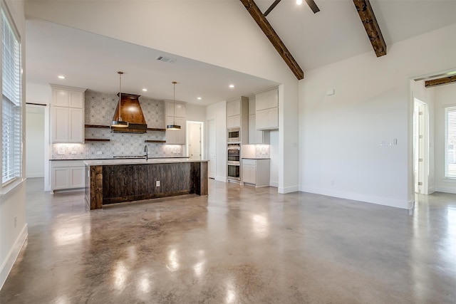 kitchen with pendant lighting, backsplash, wall chimney range hood, a large island, and beam ceiling