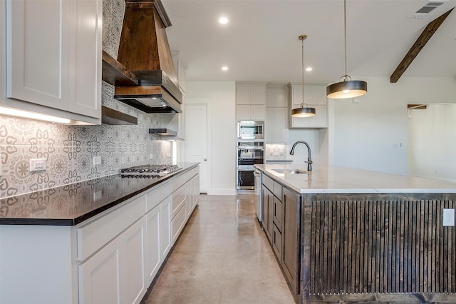 kitchen with stainless steel appliances, sink, hanging light fixtures, and a center island with sink