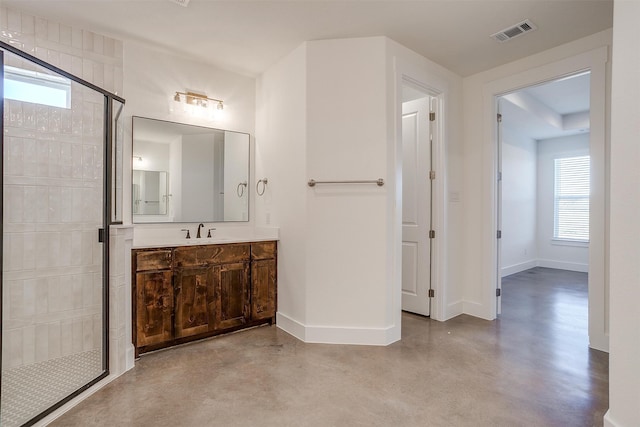 bathroom with plenty of natural light, a shower with shower door, concrete flooring, and vanity