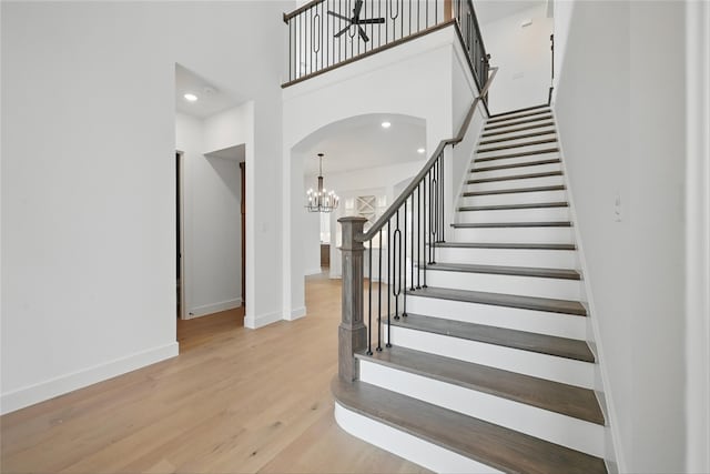 4029 Trellis Dr, Celina, TX 75078 - staircase featuring arched walkways, a chandelier, baseboards, wood finished floors, and a high ceiling