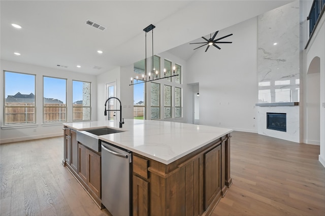4029 Trellis Dr, Celina, TX 75078 - kitchen featuring stainless steel dishwasher, open floor plan, a sink, light wood-style floors, and a large fireplace