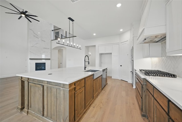 4029 Trellis Dr, Celina, TX 75078 - kitchen featuring custom range hood, a sink, stainless steel appliances, arched walkways, and brown cabinets