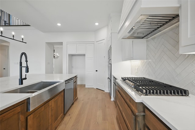 4029 Trellis Dr, Celina, TX 75078 - kitchen featuring range hood, stainless steel appliances, a sink, backsplash, and light wood-type flooring