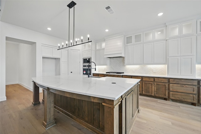 4029 Trellis Dr, Celina, TX 75078 - kitchen featuring custom range hood, built in microwave, stovetop, light wood-style floors, and decorative backsplash