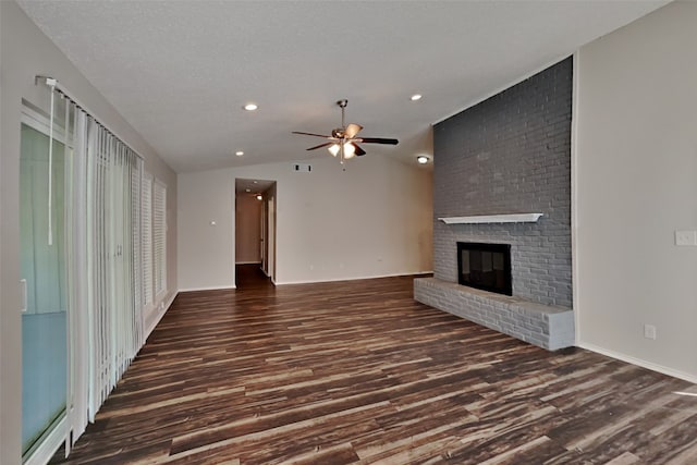 unfurnished living room with dark wood-type flooring, vaulted ceiling, a brick fireplace, ceiling fan, and a textured ceiling