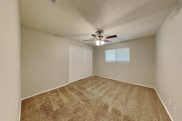 unfurnished bedroom featuring carpet flooring, ceiling fan, a textured ceiling, and a closet