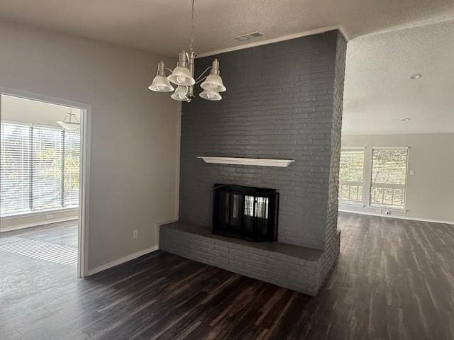 unfurnished living room with a textured ceiling, dark hardwood / wood-style flooring, a fireplace, and an inviting chandelier