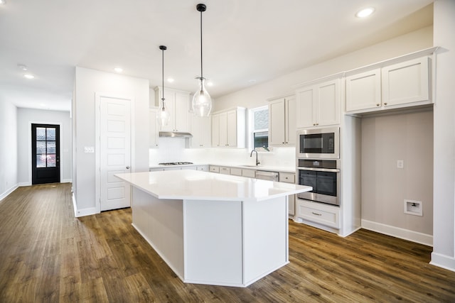 kitchen with white cabinetry, appliances with stainless steel finishes, a center island, and dark hardwood / wood-style flooring