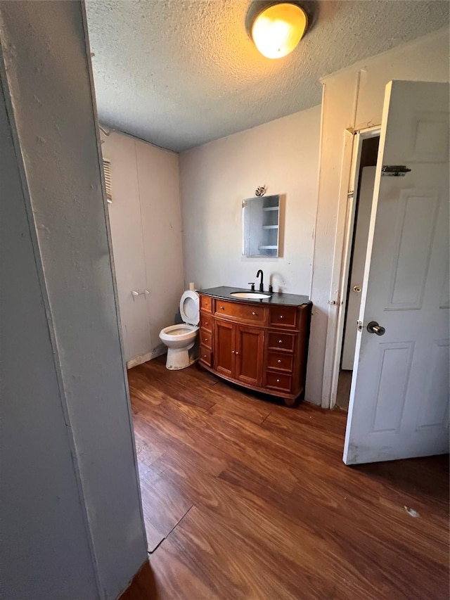 bathroom with vanity, hardwood / wood-style floors, a textured ceiling, and toilet