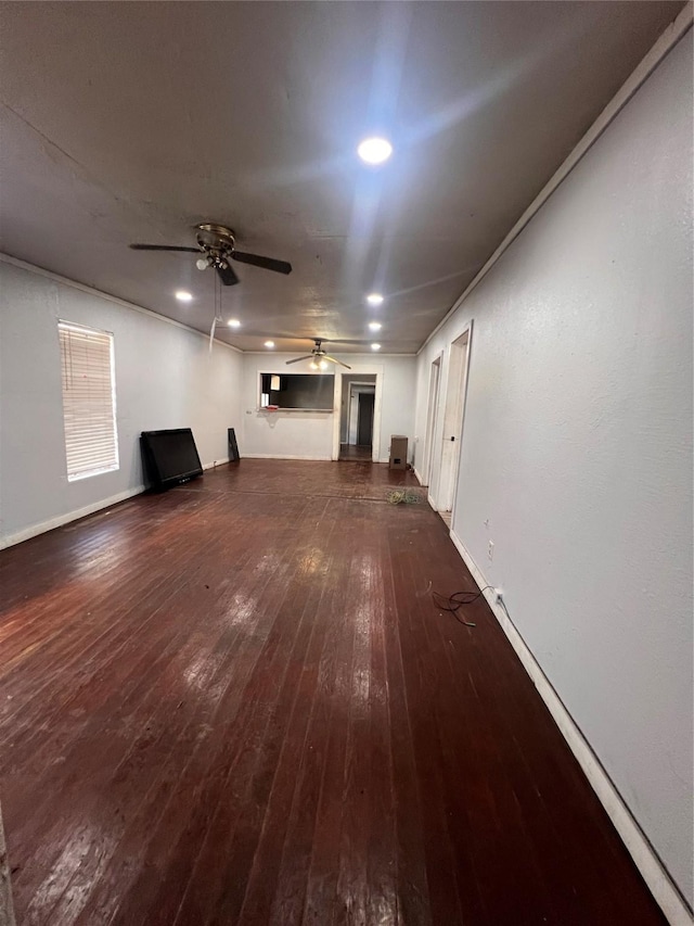 unfurnished living room featuring dark wood-type flooring and ceiling fan