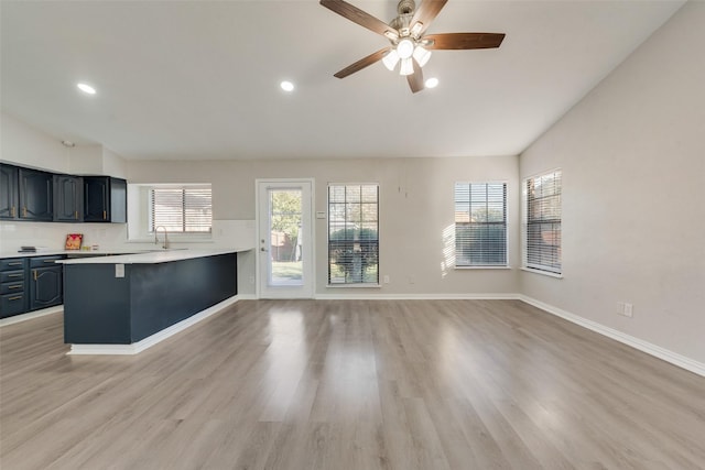 kitchen with lofted ceiling, kitchen peninsula, ceiling fan, and light hardwood / wood-style floors