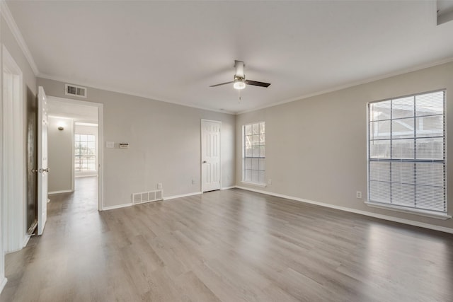 spare room featuring light hardwood / wood-style floors, ornamental molding, and a wealth of natural light