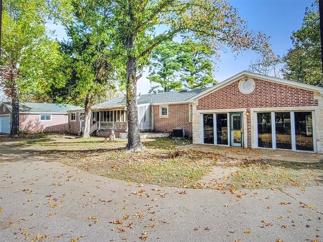 rear view of house with central air condition unit and a sunroom