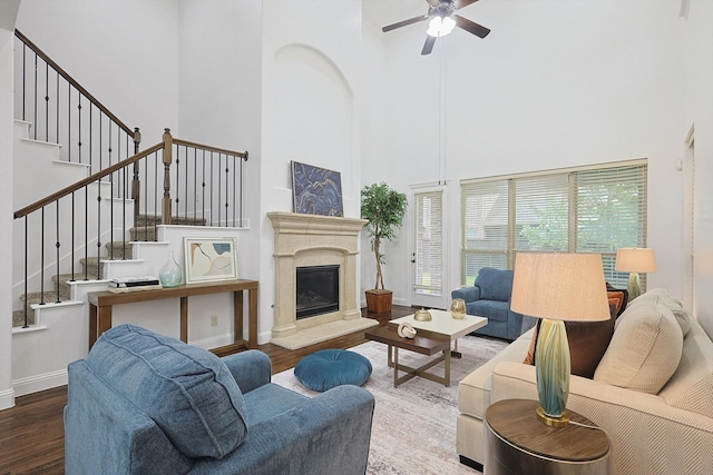 living room featuring ceiling fan, a towering ceiling, and wood-type flooring