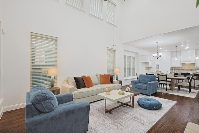 living room with dark hardwood / wood-style flooring, a chandelier, and a towering ceiling