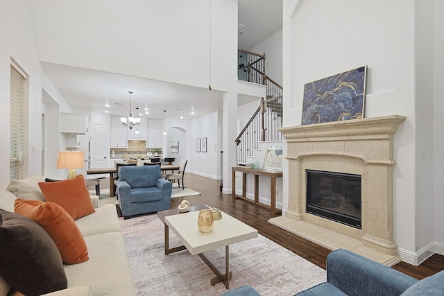 living room featuring wood-type flooring, a tile fireplace, and a notable chandelier