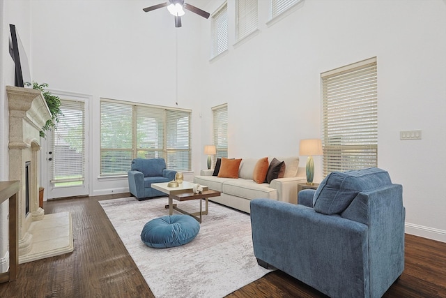 living room featuring a towering ceiling, a fireplace, dark hardwood / wood-style floors, and ceiling fan