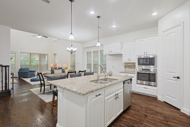 kitchen featuring appliances with stainless steel finishes, light stone countertops, sink, an island with sink, and white cabinets