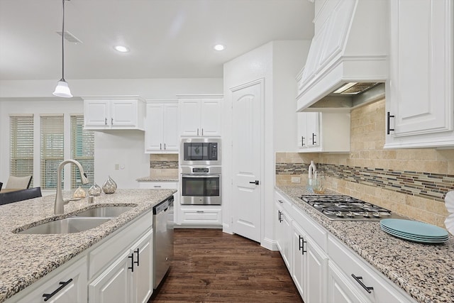 kitchen with white cabinetry, sink, appliances with stainless steel finishes, custom exhaust hood, and hanging light fixtures