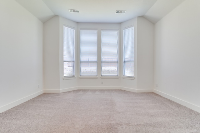 carpeted empty room featuring plenty of natural light and vaulted ceiling