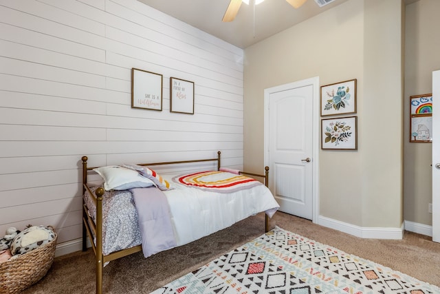 carpeted bedroom featuring wood walls and ceiling fan