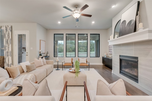 living room with a tile fireplace, hardwood / wood-style flooring, and ceiling fan