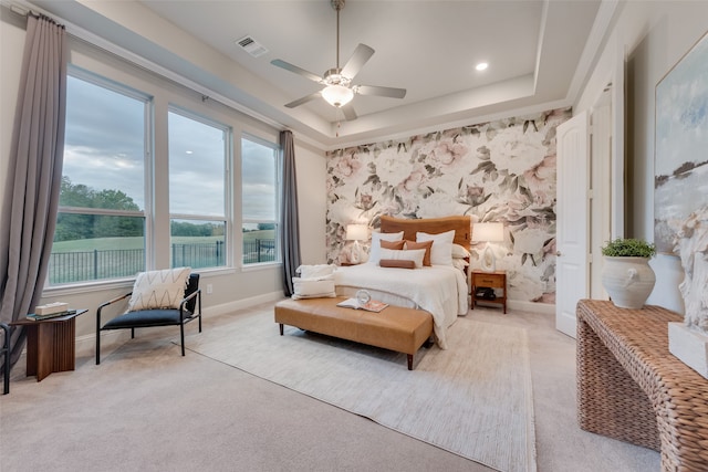 bedroom with ceiling fan, light carpet, and a raised ceiling