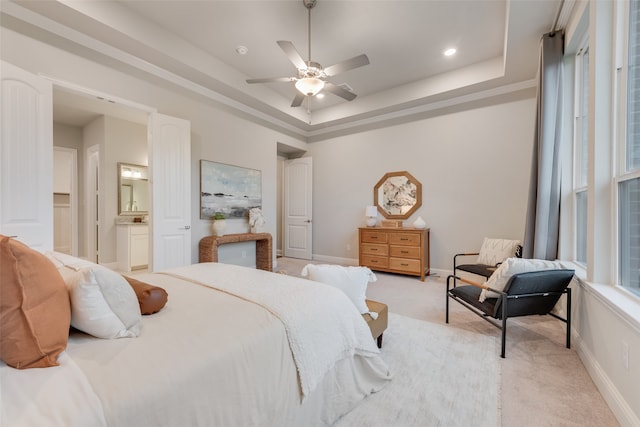 carpeted bedroom with ceiling fan, a raised ceiling, and connected bathroom