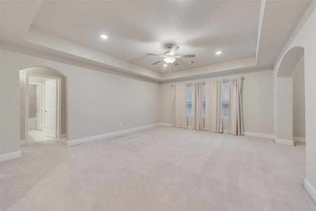 carpeted spare room with ceiling fan and a raised ceiling