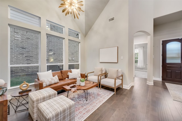 living room with dark wood-type flooring, high vaulted ceiling, and a notable chandelier