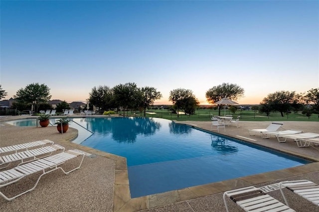 pool at dusk with a patio area