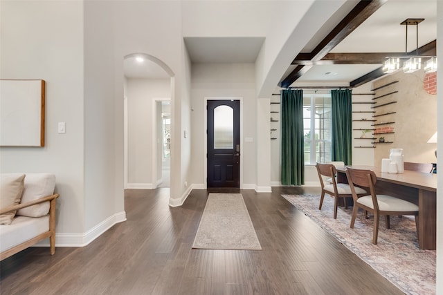 foyer featuring dark wood-type flooring and beam ceiling