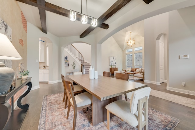 dining area with dark hardwood / wood-style floors, a chandelier, and lofted ceiling with beams