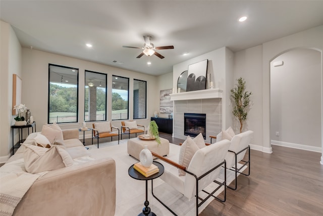 living room featuring a tile fireplace, hardwood / wood-style flooring, and ceiling fan