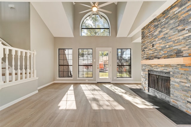 unfurnished living room featuring a healthy amount of sunlight, a stone fireplace, and light wood-type flooring