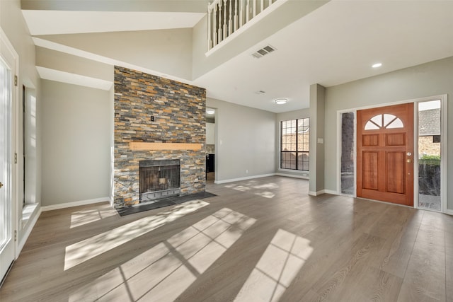 entryway with a stone fireplace, a high ceiling, and hardwood / wood-style flooring