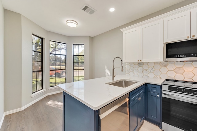 kitchen featuring blue cabinets, sink, appliances with stainless steel finishes, white cabinetry, and kitchen peninsula