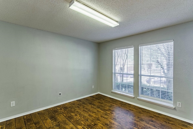 spare room featuring a textured ceiling and dark hardwood / wood-style flooring