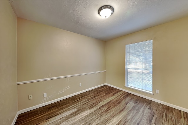 unfurnished room with hardwood / wood-style floors and a textured ceiling