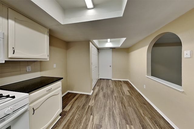 kitchen with white cabinetry, backsplash, white electric stove, a raised ceiling, and light wood-type flooring